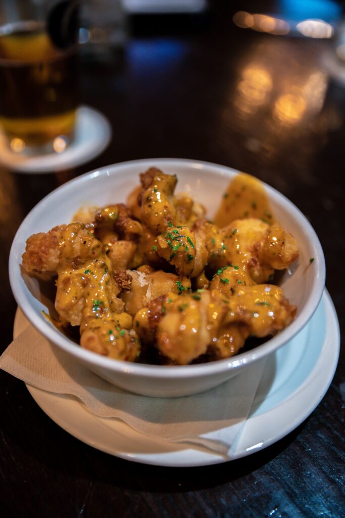 Tater tots with cheese on them in a bowl. 